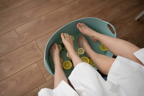 A mother and daughter indulge in a relaxing home foot spa. They are soaking their feet in a basin