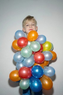 A cheerful child is standing with a delightful expression, almost hidden behind a vibrant bunch of