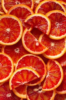 A close-up view of freshly sliced blood oranges revealing vibrant red and orange hues. The juicy