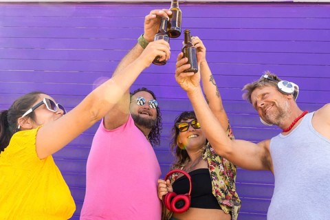 A joyful group of LGBTQIA+ friends toasting with drinks in celebration. Diverse individuals express