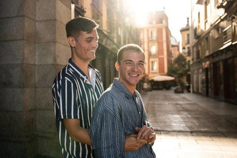 A joyful gay couple embraces while strolling down the sunlit streets of Madrid. Capturing love,