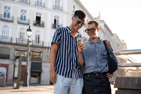 A gay couple enjoys a sunny day, exploring the lively streets of Madrid together. Smiling and