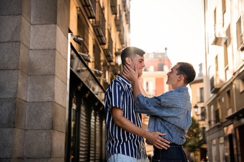 A gay couple shares a tender moment in the vibrant streets of Madrid. The warm light and intimate