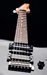 Close up of an electric guitar showcases sleek design and detailed focus on strings. Emphasizes