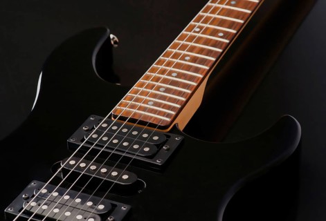 Detailed close up of an electric guitar focusing on its neck and pickups. The rich wood texture