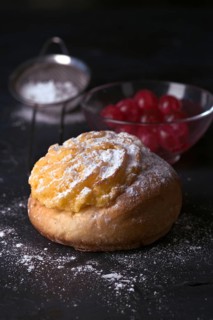 A freshly baked cream bun generously topped with a layer of velvety cream and dusted with icing