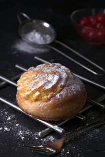 A delectable freshly baked cream bun, generously filled with smooth cream and dusted with fine