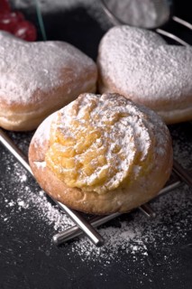 Close up view of scrumptious cream filled buns generously sprinkled with fine icing sugar,