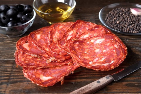 Sliced spanish cured chorizo artfully arranged on a rustic wooden table, accompanied by a bowl of