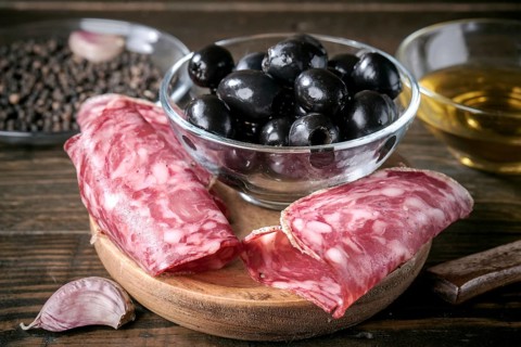 A savory Mediterranean antipasto featuring sliced spanish salami, black olives, garlic, and olive