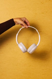 Crop hand holding headphones on golden background