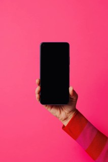 Crop anonymous person in casual clothes showing modern smartphone with empty screen while standing