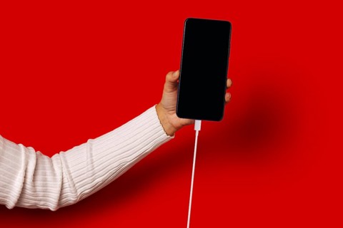 Side view of unrecognizable person in casual clothes holding smartphone with black screen while