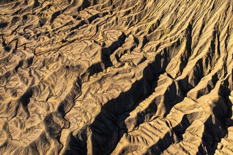Aerial view of golden desert textures at Caineville Mesa, Utah. Features notable ridges and