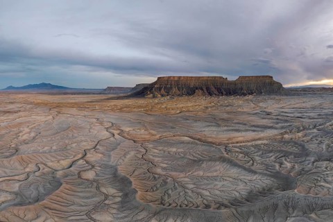 Explore the vast, rugged desert landscape featuring unique geological formations under a dramatic