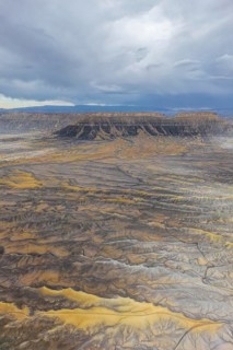 Aerial view of a rugged desert landscape featuring mesas under a cloudy sky in Hanskville, Utah.