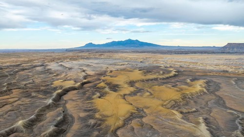 Aerial view of vast desert plains in USA with undulating terrain and patches of sand dunes, framed