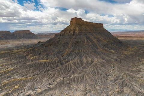 A striking aerial view of a weathered plateau with deep ridges and a barren landscape, under a