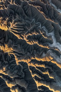 Aerial photo capturing golden desert textures and intricate patterns of Caineville Mesa, Utah. The
