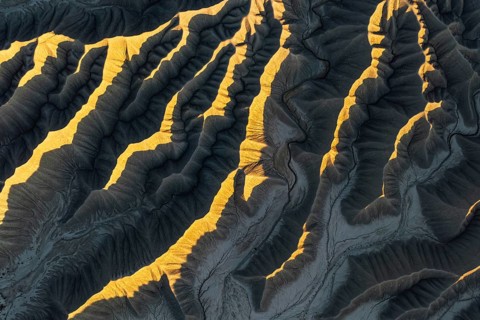 Aerial view of Caineville Mesa, Utah, showcasing dramatic ridges illuminated by golden sunlight.