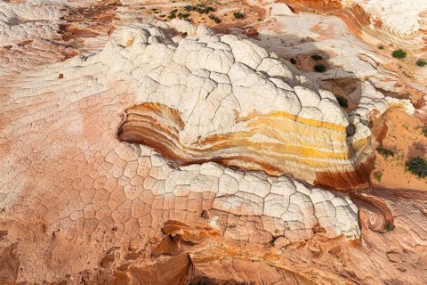 Aerial view of sandstone formations showcasing layered textures and vibrant colors in White Pocket.