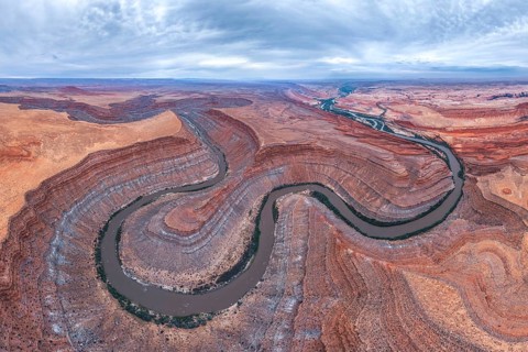Captivating aerial view of a river winding through the dramatic, layered San Juan canyon. The