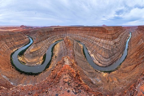 A breathtaking view of a winding river carving through a deep, red rock San Juan canyon, showcasing