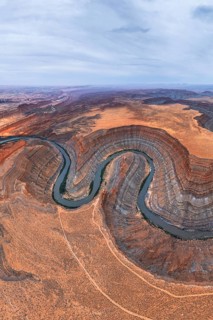 An aerial view captures a winding river cutting through a desert in San Juan canyon, showcasing