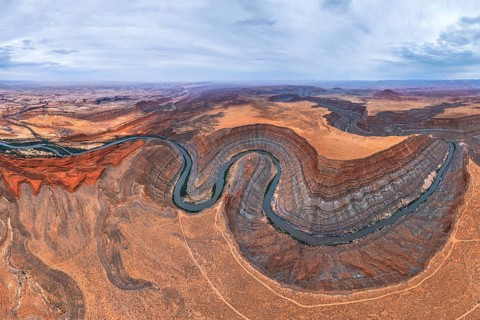 A stunning aerial view captures a meandering river cutting through the rugged San Juan canyon.