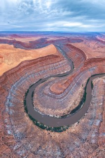 A stunning aerial view captures a serpentine river winding through layered rock formations in a