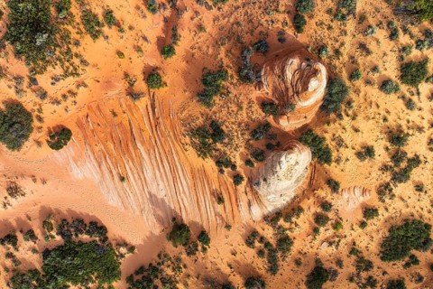 Aerial shot showcases a desert landscape with unique rock formations and contrasting vegetation in