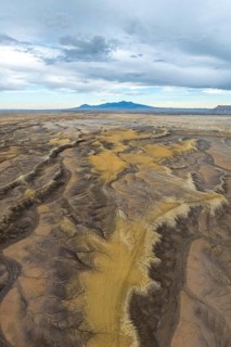 Aerial view of an expansive desert terrain featuring rugged formations and soft sand hues in