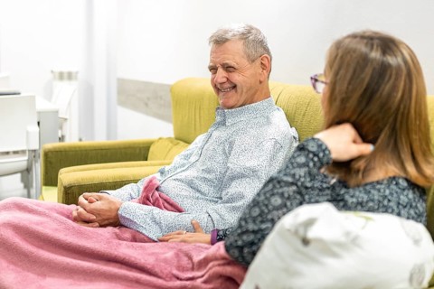 A couple with intellectual disabilities share a warm moment on a comfortable sofa, wrapped in a