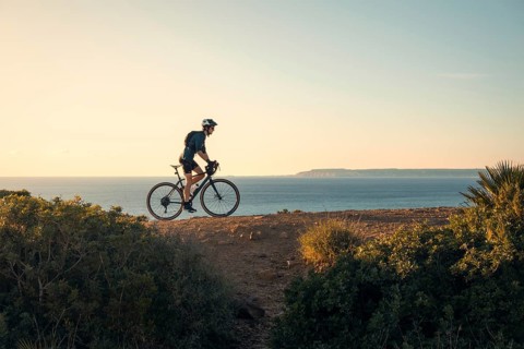 A young male cyclist rides along a scenic coastal path in Zahara de los Atunes, Cadiz, with the