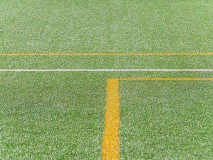 A close up view of vibrant green artificial turf with distinct yellow and white lines, creating