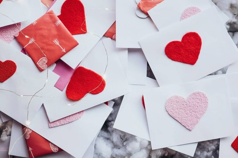 Valentine's Day envelopes adorned with red and pink felt hearts, scattered elegantly among fairy
