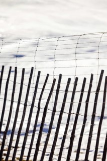 A rustic wooden fence stands in contrast against a serene snowy backdrop, showcasing a blend of