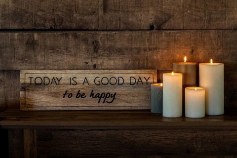 A motivational sign with the words Today is a good day to be happy rests on a rustic wooden shelf,