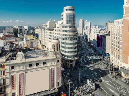 A bustling urban Madrid scene captures the vibrant life of Gran Via street flanked by historic