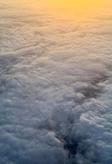 Captured from above, this image showcases a stunning blanket of fluffy clouds illuminated by a warm