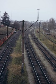 Overhead view of curved railway tracks in a misty, overcast setting. The tracks run alongside a