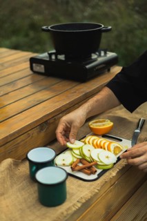 Cropped unrecognizable person preparing ingredients for mulled wine outdoors, arranging sliced