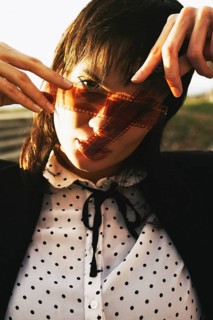 Woman in polka dot blouse, holding film strip against sunlight, creating an artistic shadow over