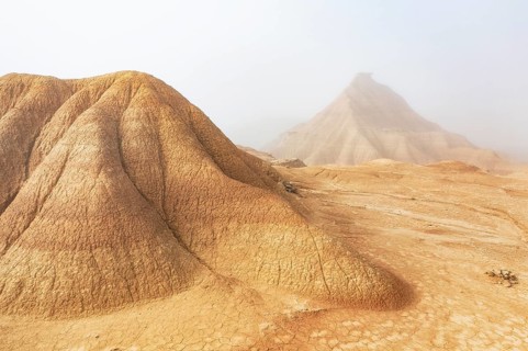 A captivating desert scene with majestic eroded hills shrouded in light mist, creating a mysterious