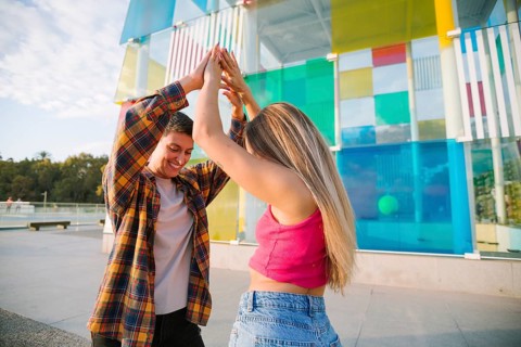 A happy lesbian couple dances joyfully in a vibrant outdoor setting, celebrating love and diversity