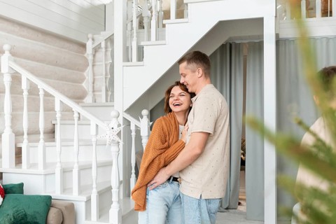 A joyful couple shares a loving embrace inside a well-decorated home, conveying warmth and