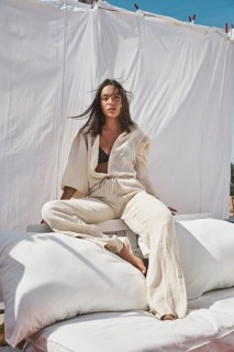 A young woman lounges on a rooftop, basking in the warmth of summer sun Dressed in light, flowing