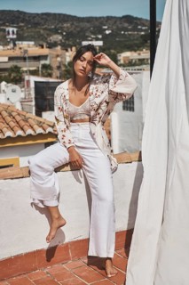 Young woman enjoying a sunny day on a rooftop, dressed in stylish bohemian attire The scenery