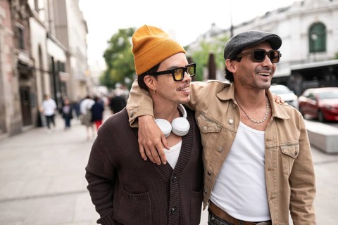 A joyful colombian gay couple enjoying a casual city walk. Both are wearing sunglasses and
