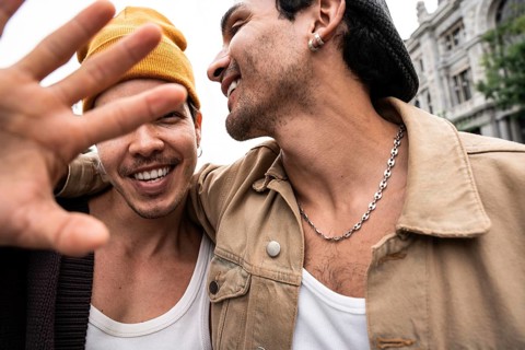 A happy gay couple enjoys a day out, displaying affection and a carefree attitude. The focus is on